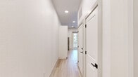 Located at 306 Melba St in Dallas, TX, this single-story space showcases a clean, contemporary design with a consistent palette of crisp white walls and light wood-tone flooring carried throughout every room. The open-concept kitchen serves as the heart of the home, outfitted with floor-to-ceiling white shaker cabinetry, a quartz-topped island with an undermount sink and matte black fixtures, and a full suite of stainless steel appliances. A statement pendant light with a gold geometric shade adds a striking focal point, while glass doors open to an outdoor area, filling the space with natural light. A sliding barn door with natural wood paneling conceals a stacked washer and dryer, blending practicality with design. The hallway is lined with recessed lighting and features paneled interior doors with matte black hardware, maintaining a cohesive modern aesthetic. Bedrooms offer light-filled interiors with large windows overlooking the surrounding neighborhood, and one room includes built-in shelving for added functionality. The primary bedroom connects to a walk-in closet with built-in shelving. Bathrooms feature white vanity cabinetry with matte black hardware, with one bath highlighted by bold geometric accent wallpaper and a round mirror, adding visual contrast to the otherwise neutral interior.
