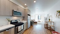 Located at 532 Union St in Oakland, California, this modern single-floor residence offers a well-designed open-concept layout that seamlessly connects the kitchen, dining, and living areas. The kitchen is outfitted with stainless steel appliances — including a gas range, dishwasher, microwave, and refrigerator — complemented by light wood-tone cabinetry, white quartz countertops, and warm hardwood-style flooring that extends throughout the main living spaces. The spacious living room benefits from large windows that invite generous natural light, creating a bright and airy atmosphere. The bedroom features a large window for additional natural light, crisp white walls, and a calm, restful ambiance with warm accent decor. A dedicated office space provides a quiet work-from-home setup, complete with a clerestory window, open shelving, and room for a full desk. The bathroom includes a clean, contemporary vanity with light wood cabinetry and quartz surfaces, with tile flooring for a polished finish. A hallway laundry closet houses a stacked washer and dryer, adding everyday convenience. Throughout, the unit maintains a cohesive modern aesthetic with neutral tones, clean lines, and thoughtful finishes.