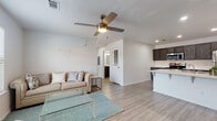 Located at 1603 W Walnut St in Rogers, Arkansas, this single-story unit offers a thoughtfully designed open-concept floor plan that seamlessly connects the living, dining, and kitchen areas. Light wood-look flooring runs throughout, complementing the clean, neutral color palette and creating a bright, cohesive atmosphere.

The living area is generously proportioned, featuring a ceiling fan with light fixture and large windows dressed with horizontal blinds that allow ample natural light to fill the space. The kitchen is a standout feature, showcasing dark espresso cabinetry, crisp white quartz countertops, and a large peninsula island with an undermount sink — ideal for both meal preparation and casual dining. A full suite of stainless steel appliances, including a refrigerator, range, over-the-range microwave, and dishwasher, completes the kitchen.

The unit includes two well-sized bedrooms, each equipped with ceiling fans and windows that bring in natural light. Both rooms offer closet storage and maintain the consistent wood-look flooring found throughout the home. The bathroom features dark cabinetry with white countertops, a full tub-shower combination, and a large mirror, maintaining the modern aesthetic carried throughout the space. The overall design is clean, contemporary, and move-in ready.