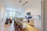 Located in Dania Beach, FL, this modern 2-bedroom, 2-bathroom residence offers a thoughtfully designed open-concept layout with clean lines and contemporary finishes throughout. Light wood flooring flows seamlessly across the entire unit, complementing the bright, airy atmosphere created by high ceilings and abundant natural light.

The kitchen is a standout feature, showcasing sleek high-gloss white cabinetry, quartz countertops, a white tile backsplash, and a full suite of stainless steel appliances including a French door refrigerator. A central island with seating anchors the space and connects effortlessly to the living area, which is illuminated by track and pendant lighting. The living room opens directly to a private balcony through floor-to-ceiling windows, offering expansive outdoor views.

The primary bedroom is a serene retreat with soft neutral tones and generous closet space. Both bathrooms are finished with striking marble-style tile flooring and walls, featuring floating vanities with white quartz counters, backlit mirrors, and matte black fixtures that add a sophisticated contrast. The unit also includes a dedicated laundry area and utility room. Four closets provide ample storage throughout the residence.