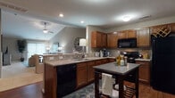 Located at 42 Hallowell Dr in Columbus, Ohio, this single-floor home offers a well-designed layout that balances comfort and functionality. The open-concept kitchen is a highlight of the space, featuring rich wood cabinetry, stone-look countertops, hardwood flooring, black appliances, and a central island for additional prep and storage. The kitchen flows seamlessly into the dining and living areas, where vaulted ceilings and a ceiling fan create a sense of openness and airflow. The living area is finished with plush carpeting and neutral-toned walls, providing a warm and inviting atmosphere. The bedroom is generously proportioned, with soft carpet underfoot, natural light from multiple windows, and ample room for full-sized furniture. Two bathrooms serve the home — one featuring tile flooring, a wood vanity, and a shower with curtain, and another with tile floors and a glass-enclosed shower-tub combination. A dedicated office or flex room offers carpeted flooring and a window for natural light, making it a practical space for work or study. Throughout the home, neutral earth-tone walls, consistent flooring transitions, and recessed lighting contribute to a cohesive and polished interior aesthetic.