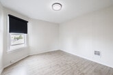 Located at 1831-1835 Harmon St in Berkeley, CA, this single-room space offers a well-designed bedroom that maximizes functionality within a compact footprint. The room features light-toned hardwood-style flooring throughout, lending a clean and contemporary aesthetic that brightens the interior. Crisp white walls and white baseboards contribute to an open, airy feel, while a flush-mount ceiling light with a decorative surround provides overhead illumination. Natural light enters through a window fitted with a blackout roller shade, offering flexible light control and privacy. The bedroom is equipped with two closets: a set of mirrored sliding-door closets providing generous storage with built-in shelving, and an additional set of white panel sliding doors. A wall-mounted heater vent ensures climate comfort year-round. A dark-paneled door with modern hardware serves as the room's entry point. The overall design is neutral and move-in ready, with a minimalist character that allows for versatile furnishing arrangements. The space is well-suited for those seeking a straightforward, low-maintenance living environment in the vibrant Berkeley neighborhood.
