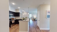 Located at 25 E Revere Blvd in Huntsville, Alabama, this single-floor residence offers a thoughtfully designed open-concept layout that blends functionality with modern style. The kitchen is a standout feature, showcasing dark espresso cabinetry, granite countertops, a subway tile backsplash, stainless steel appliances, and a peninsula with bar seating — all illuminated by sleek pendant lighting. Warm hardwood-style flooring flows seamlessly from the kitchen into the living area, where French doors invite abundant natural light and provide views of the surrounding neighborhood. The bedrooms are carpeted for comfort, with large windows that brighten each room with natural light. The primary bedroom offers generous space and direct access to a private bathroom featuring a granite vanity, dark cabinetry, and a tub-shower combination. A secondary bathroom includes a clean, all-white tub-shower surround. A dedicated in-unit laundry area accommodates a full-size washer and dryer, complete with overhead shelving for added storage. Neutral wall tones and clean finishes throughout create a bright, welcoming ambiance suited for everyday living.