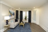 This thoughtfully designed single-floor residence offers a seamless blend of modern style and functional living. The gourmet kitchen is a standout feature, showcasing floor-to-ceiling white shaker cabinetry with crown molding detail, a striking two-tone island with a crisp white quartz countertop, a classic subway tile backsplash, and a full suite of stainless steel appliances. Pendant lighting adds an elegant finishing touch overhead, while wood-look flooring grounds the space warmly.

The living room exudes sophistication with crown molding, recessed lighting, rich hardwood flooring, and large windows dressed in dark drapes that invite natural light while providing privacy.

The primary bedroom is generously proportioned, featuring plush carpeting, a ceiling fan, and direct access to an outdoor balcony. Additional bedrooms offer flexibility, each with ceiling fans, carpet flooring, and access to natural light — one with its own balcony door.

The bathrooms are finished to a high standard, featuring marble-style tile surrounds, a soaking tub-shower combination with glass enclosure in one bath, and a sleek walk-in glass shower with white quartz vanity countertops in another. Clean white cabinetry and modern fixtures complete the polished aesthetic throughout.