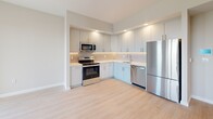 Located at 183-03 Hillside Ave in Jamaica, NY, this thoughtfully designed one-bedroom, one-bathroom residence offers a bright and modern living experience. The open-concept living and kitchen area is anchored by light hardwood-style flooring that flows throughout the space, creating a cohesive and airy feel. Large windows invite generous natural light and frame expansive outdoor views of the surrounding neighborhood.

The kitchen is outfitted with sleek grey cabinetry, white quartz-style countertops, a classic grid-pattern tile backsplash, and a full suite of stainless steel appliances including a range, microwave, dishwasher, and refrigerator — offering both style and functionality. Recessed lighting adds a polished finish to the kitchen area.

The bedroom is a well-proportioned retreat with large windows that continue the theme of natural light and open views. Two closets provide ample storage throughout the unit. A private balcony accessible from the living area offers an outdoor extension of the living space.

The bathroom features a full soaking tub with a striking two-tone tile surround — crisp white vertical tiles accented by a bold black border — lending a clean, contemporary aesthetic. Neutral tones throughout the residence create a calm, modern ambiance suited for everyday living.