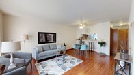This three-floor home offers a well-organized layout across its levels, each serving a distinct purpose. The main floor centers around an open-concept living and dining area finished with warm hardwood-style flooring. A large window at the front of the living room draws in natural light, creating a bright and welcoming atmosphere. The dining area connects directly to the kitchen via a pass-through window, enhancing the sense of openness. The kitchen is efficiently designed with rich dark wood cabinetry, light countertops, white appliances including a gas range, dishwasher, and refrigerator, and durable tile-style flooring. A half bathroom with stone-toned flooring and clean, simple fixtures is also found on this level.

The upper floor contains the bedrooms, each carpeted for comfort and equipped with a closet and window for natural light. A full bathroom on this level features warm wood cabinetry, a vanity with a large mirror, and a medicine cabinet with open shelving.

The lower level offers a finished recreation room with carpeting, a drop ceiling, and a small window. This versatile space is well-suited for leisure and entertainment, providing a comfortable retreat separate from the main living areas.