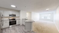 Located at 1070 Kenmore Dr in Clayton, NC, this single-story, 2-bedroom, 2-bathroom residence offers a thoughtfully designed layout with a clean, modern aesthetic. The open-concept kitchen flows seamlessly into the living area, creating a connected and functional living space. The kitchen is outfitted with white shaker-style cabinetry, granite countertops, stainless steel appliances including a range, microwave, and refrigerator, and a peninsula with an undermount sink — ideal for both meal preparation and casual dining. Wood-look plank flooring anchors the kitchen and transitions into soft carpet in the living and bedroom areas. Each bedroom is carpeted and features a ceiling fan, ample natural light from large windows with blinds, and dedicated closet space. The primary bedroom includes a spacious walk-in closet with multi-tiered wire shelving. The bathrooms are finished with granite-topped vanities, grey cabinetry, hardwood-style flooring, and well-lit mirrors. One bathroom features a full soaking tub with shower. The overall ambiance is bright, neutral, and move-in ready, with consistent finishes throughout that contribute to a cohesive and comfortable living environment.