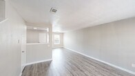 This two-story residence offers a well-organized layout with distinct living spaces across both levels. The main floor features an open living area finished with light gray luxury vinyl plank flooring that runs throughout, complemented by neutral gray walls and crisp white trim. A large window on the main level allows ample natural light to fill the space, creating a bright and airy atmosphere. A staircase with dark carpet connects the two floors and adds a visual contrast to the otherwise light interior.

The kitchen is thoughtfully designed with white shaker-style cabinetry, marble-patterned laminate countertops, a stainless steel double-basin sink, and stainless steel appliances including an electric range and over-the-range microwave. A pass-through window opening toward the living area enhances the sense of connectivity between spaces.

Upstairs, the bedrooms are finished with plush neutral carpet, textured walls, and windows that bring in natural light. Each room offers a comfortable, private retreat with closet access. The bathroom is appointed with a white vanity, a soaking tub, and large-format marble-look wall tiles, delivering a clean and polished aesthetic. Textured ceilings are present throughout the home, adding a classic architectural detail to each room.