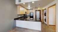 Located at 57 Fourth St E in the heart of downtown Saint Paul, Minnesota, this single-floor residence offers a thoughtfully designed layout with functional, modern finishes throughout. The kitchen is a standout feature, showcasing dark granite countertops that contrast elegantly with light maple cabinetry. It is fully equipped with black appliances, including a refrigerator and dishwasher, alongside a stainless steel range and sink. A peninsula-style breakfast bar extends the counter space and provides a natural divide between the kitchen and the adjoining living area. Conveniently tucked nearby is an in-unit stacked washer and dryer, adding everyday practicality. The bedrooms are bright and inviting, with neutral walls, speckled terrazzo-style flooring, and windows fitted with wooden blinds that allow for natural light while maintaining privacy. Warm-toned wood doors and trim carry a consistent, cohesive aesthetic throughout the unit. The bathroom is clean and efficiently laid out, featuring a full tub-shower combination with a curtain rod, a grab bar, and matching neutral tones that complement the rest of the space. The overall design is understated and practical, making this a comfortable and move-in ready residence in a prime urban Saint Paul location.