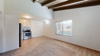 Located at 7781 Archibald Ave in Rancho Cucamonga, CA, this one-bedroom, one-bathroom apartment offers a compact yet efficiently designed single-floor layout. A defining architectural feature is the vaulted ceiling with exposed dark wood beams and wood plank detailing, adding warmth and visual height to the living spaces.

The open-concept kitchen and living room share a continuous, light-filled space. The kitchen is equipped with stainless steel appliances — including a full-size refrigerator and electric range — complemented by light cabinetry, dark countertops, a tile backsplash, and tile flooring. The living area transitions to soft carpeting and benefits from multiple windows with blinds that bring in natural light and outdoor views.

The bedroom is a well-proportioned retreat, also featuring the signature vaulted beam ceilings, plush carpeting, and a window that provides natural light. A dedicated closet offers convenient storage. A wall-mounted heating unit serves the bedroom.

The bathroom includes a clean white vanity with a single basin sink, mirrored medicine cabinets, and bright overhead lighting, maintaining a simple and functional aesthetic throughout. The unit's entry area features tile flooring that transitions smoothly into the carpeted living space.