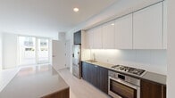 Located at 45 Lansing Street in San Francisco's SoMa neighborhood, this thoughtfully designed one-bedroom, one-bathroom residence offers a clean, contemporary aesthetic throughout its well-utilized single floor. Light-toned wood flooring flows through the main living areas, complemented by crisp white walls that maximize the sense of brightness and space.

The kitchen is a standout feature, showcasing a sleek galley-style layout with dark wood cabinetry contrasted against high-gloss white upper cabinets that extend to the ceiling for ample storage. Stainless steel appliances — including a gas range, wall oven, and French door refrigerator — are paired with a neutral stone countertop and a large central island, making the space both functional and stylish.

The bedroom is carpeted for comfort and features a generous sliding-door closet with built-in wire shelving. A wall of floor-to-ceiling sliding glass doors opens to a private outdoor patio, allowing natural light to pour in and providing views of the surrounding urban landscape.

The bathroom is elegantly finished with large-format floor tiles, a soaking tub framed by full marble-slab surround, a modern floating vanity, and linear LED ceiling lighting that adds a refined, spa-like ambiance. The living area is bright and open, with natural light reflected off glossy wall panels.