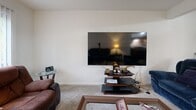 Located at 2809 Curry Pkwy in Madison, Wisconsin, this single-floor, 2-bedroom, 1-bathroom home offers a practical and comfortable layout. The living room is a welcoming space filled with natural light from large windows dressed in vertical blinds, offering views of surrounding greenery. The room provides ample space for seating and entertainment, including a wall-mounted television area.

The kitchen features warm wood cabinetry, stainless steel appliances including a refrigerator, gas range, and microwave, along with light hardwood-style flooring that gives the space a clean and modern feel. It connects conveniently to a hallway leading to the rest of the home.

Both bedrooms are carpeted and equipped with ceiling fans. The primary bedroom is a comfortably sized retreat featuring a built-in closet with sliding panel doors, a window with outdoor views, and enough space for a full bedroom set. The second bedroom also includes a window with natural light and similarly soft carpeted flooring.

The bathroom is neatly appointed with large-format dark tile surrounding the tub-shower combination, complemented by tile flooring. A dedicated closet provides additional storage within the home. The overall ambiance is bright, clean, and functional — well-suited for comfortable everyday living.