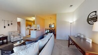 This single-floor residence offers a practical and comfortable layout designed to maximize the use of its living spaces. The open-concept living area is finished with neutral-toned carpet and connects seamlessly to both the dining area and kitchen, creating a cohesive and functional flow throughout. The living room benefits from natural light through a sliding glass door that opens to an outdoor view, lending the space an airy, welcoming quality.

The galley-style kitchen is efficiently arranged with warm honey-toned cabinetry lining both walls, providing generous storage. White appliances include a refrigerator, range, microwave, and dishwasher, complemented by light countertops and tile flooring.

Adjacent to the kitchen, the dining area is defined by a chandelier overhead and is large enough to accommodate a full dining set, with a closet nearby adding practical storage.

The bedroom is a comfortable, carpeted retreat featuring a window with an outdoor view, offering natural light and a sense of openness. The bathroom features tile flooring, a full tub-shower combination, a vanity with ample cabinetry, and a mirrored medicine cabinet. Throughout the space, a consistent neutral palette creates a calm and cohesive ambiance.