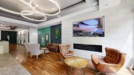 Located at 8204 Baltimore Ave in College Park, Maryland, this thoughtfully designed amenity floor offers a sophisticated and welcoming environment across a generously sized single-level footprint. The main lobby greets visitors with rich hardwood flooring, large-format tile, and a striking sculptural ring chandelier suspended from a coffered ceiling, setting a refined tone throughout. A built-in linear fireplace framed in white subway tile anchors one wall, complemented by tufted leather seating and accent chairs arranged around a natural wood coffee table, creating an inviting lounge atmosphere. A live moss wall installation and bold teal accent wall add vibrant organic touches to the space. Adjacent to the lobby, a well-appointed co-working and social lounge area features coffered ceilings with pendant copper lighting, ample built-in banquette seating, individual desk stations along paneled walls, and large windows that flood the room with natural light and views of the surrounding streetscape. The entry corridor includes a mail room and leads seamlessly to a fitness center visible through glass partitions. Multiple elevator bays with stainless steel doors are conveniently positioned near a reception desk, ensuring smooth circulation throughout. The overall ambiance balances contemporary style with functional comfort, making it an exceptional communal space.