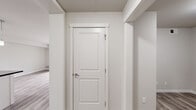 Located at 5601 Gordon Road in Regina, Saskatchewan, this two-bedroom, one-bathroom unit offers a thoughtfully designed layout that maximizes functionality and comfort. The open-concept kitchen and living area serves as the heart of the home, featuring crisp white cabinetry, bold dark granite countertops, a large peninsula island with pendant lighting, and a full suite of black appliances including a refrigerator, electric range, and over-the-range microwave. Light wood-tone luxury vinyl plank flooring runs throughout the entire unit, lending a cohesive and contemporary feel. The living area is bright and airy, with a sliding glass door that opens directly onto a private balcony overlooking the surrounding neighbourhood. The primary bedroom offers a comfortable footprint, a sliding-door closet with built-in shelving, and a window that invites natural light. The second bedroom is equally well-lit, with its own window and clean neutral finishes. Connecting the spaces are two hallways lined with clean white panel doors and built-in storage areas. The bathroom is finished with matching flooring and features a full soaker tub and shower combination. Neutral tones and consistent finishes throughout the unit create a clean, modern ambiance.