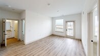 Located in Aurora, CO, this thoughtfully designed one-bedroom, two-bathroom residence offers a clean, modern aesthetic across a single floor. The open-concept living area features light-toned hardwood-style flooring and bright white walls, with natural light streaming in through windows and a glass-paned exterior door that opens to an outdoor balcony area, providing views of the surrounding landscape.

The kitchen is a standout feature, showcasing white shaker-style cabinetry extending to the ceiling, a subway tile backsplash, quartz countertops, stainless steel appliances, and a generous center island with pendant lighting and a undermount sink — ideal for both cooking and entertaining. In-unit laundry is conveniently accessible nearby.

The primary bathroom is elegantly finished with a dual-sink vanity featuring white cabinetry, quartz countertops, black hardware accents, and a soaking tub with tiled surround and a curved shower rod. The space connects directly to the bedroom, which is carpeted and benefits from natural light through windows with open views.

Two walk-in closets provide exceptional storage, each carpeted and outfitted with multi-level shelving and hanging rods along multiple walls. The second bathroom mirrors the refined design language found throughout the home, completing this well-appointed residence.