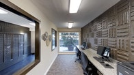 The business center at 3950 Leland in San Diego is a single-story workspace thoughtfully designed to support productivity in a polished, comfortable environment. The room features a long granite-topped workstation running along one wall, accommodating multiple computer workstations with ample desk space for individual use.

A standout feature of the space is the textured accent wall, clad in a rich, dimensional stone-like tile pattern in earthy brown tones, adding a sophisticated architectural element that elevates the overall aesthetic. This is complemented by neutral beige walls and patterned carpeting that contributes warmth and visual interest underfoot.

Natural light enters through a large picture window at the end of the room, offering a view of a landscaped outdoor area with potted greenery, creating a pleasant connection to the exterior. Overhead, recessed fluorescent lighting ensures consistent, even illumination throughout the workspace.

Framed windows on the adjacent wall provide additional visual openness, while decorative wall art adds a subtle personal touch. The overall ambiance is clean, professional, and welcoming—well-suited for residents or tenants seeking a dedicated space for work or study.