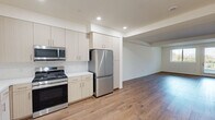 This single-story, 1-bedroom, 1-bathroom residence delivers a clean, modern aesthetic across a well-organized floor plan. Light wood-look flooring flows seamlessly throughout the main living areas, anchoring the open-concept design that connects the living room, dining area, and kitchen into one cohesive space. The living room is bright and inviting, featuring large windows and a glass door that invite abundant natural light and provide outdoor views. The kitchen is equipped with light wood cabinetry extending to the ceiling for generous storage, white quartz countertops, a subway tile backsplash, and a full suite of stainless steel appliances including a gas range, over-the-range microwave, dishwasher, and refrigerator. The bedroom is a comfortable, well-lit retreat with a window overlooking the outdoors and warm hardwood-style flooring. A spacious walk-in closet with multi-level shelving and hanging rods offers substantial storage. The bathroom features a long double-sink vanity with light wood cabinetry, white countertops, large mirrors, and a soaking tub with a marble-style tile surround. A hallway entry with a dedicated closet completes this efficiently designed residence.