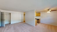 This single-floor residence at Hillcrest Village, located at 865 Broadway Avenue in Holbrook, New York, offers a practical and well-organized layout designed for comfortable everyday living. The living area is generously proportioned, finished with neutral wall-to-wall carpeting that carries throughout the main spaces, and benefits from natural light admitted through double windows. A wall-mounted HVAC unit and baseboard heating provide year-round climate control.

The kitchen is arranged in a galley configuration, featuring warm-toned wood cabinetry that lines both sides, offering ample upper and lower storage. Stainless steel appliances include a gas range, built-in microwave, refrigerator, and dishwasher, complemented by light-toned countertops and tile flooring. A pass-through opening connects the kitchen to the living space, creating a cohesive flow between the two areas.

The bedroom is a well-sized room with carpeted flooring, neutral walls, and a double-door closet providing substantial storage. The bathroom features a clean white vanity with an integrated sink and a large mirror above. Additional closet space is visible elsewhere in the layout, further enhancing storage capacity throughout the residence. The overall interior presents a clean, functional aesthetic well-suited for daily living.