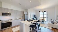 Located in Miami's vibrant Coconut Grove neighborhood, this thoughtfully designed one-bedroom, one-bathroom residence offers a sleek, modern living experience. The open-concept kitchen and living area serves as the heart of the home, anchored by a large central island with bar seating and crisp white quartz countertops. Light wood-grain cabinetry, a white subway tile backsplash, and a full suite of stainless steel appliances — including a French door refrigerator, electric range, built-in microwave, and dishwasher — complete the well-appointed kitchen. Warm hardwood flooring flows throughout the main living areas, complementing the bright, neutral palette.

The living room is bathed in natural light through expansive floor-to-ceiling windows that frame sweeping views of the Miami skyline and lush surroundings. A statement gold-and-black multi-arm chandelier adds a bold, contemporary touch to the space. The bedroom continues the floor-to-ceiling window theme, offering the same stunning panoramic views and an airy, sun-filled atmosphere. A dedicated walk-in closet with wire shelving provides ample storage. The bathroom features an extended vanity with stone countertops and is conveniently paired with an in-unit stacked washer and dryer.