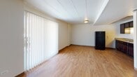 Located at 12500 Fairview Ave in Blue Island, Illinois, this single-floor unit offers a practical and well-maintained living space designed for everyday comfort. Throughout the unit, warm wood-style laminate flooring provides a cohesive and inviting foundation, complemented by clean white walls and tiled ceilings that keep the interiors feeling bright and open.

The main living area is generously sized, featuring a large window dressed with vertical blinds that allow ample natural light to fill the room. A black refrigerator is conveniently situated nearby, highlighting the open layout's versatility.

The kitchen is outfitted with rich, dark espresso cabinetry — both upper and lower — paired with granite-style countertops and a double stainless steel sink. A black gas range with an overhead exhaust hood completes the functional cooking space.

The bedroom features a window with exterior views, delivering natural light and a connection to the outdoors, along with a wall-mounted air conditioning unit and floor-level heating vents for year-round climate control.

The full bathroom includes a tiled tub-and-shower combination, a single-basin vanity set in dark cabinetry with under-sink storage, a wall-mounted mirror, and a toilet — all finished with wood-style flooring for a clean, consistent aesthetic throughout.