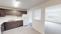 Located at 579 E Main St in Middletown, NY, this one-bedroom, one-bathroom unit offers a practical and well-designed single-floor layout. The kitchen is a standout feature, showcasing rich dark-stained cabinetry with silver hardware, white appliances including an electric range and refrigerator, light-colored countertops, and light wood-style flooring. A built-in pass-through window connects the kitchen to the adjacent living area, enhancing the open feel of the space. The living area is carpeted and receives natural light, creating a warm and comfortable atmosphere. The bedroom is a generously sized, quiet retreat with plush carpeting, a large window with blinds that allows natural light to fill the room, and access to a dedicated walk-in closet outfitted with wire shelving and hanging rods for ample storage. The full bathroom features light tile flooring, a glass-door shower stall, toilet, and vanity, all set within a clean, bright space. Throughout the unit, neutral wall tones and consistent finishes contribute to a cohesive and move-in-ready environment.