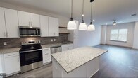 Located at 4205 Third Ave S in Birmingham, Alabama, this single-floor residence offers a thoughtfully designed, contemporary living space with modern finishes throughout. The open-concept kitchen serves as a central highlight, featuring crisp white shaker cabinetry, granite countertops, a textured tile backsplash, and a full suite of stainless steel appliances including a range, microwave, dishwasher, and refrigerator. A center island with matching granite provides additional prep space and is illuminated by a trio of stylish pendant lights. Wood-style luxury vinyl plank flooring flows throughout the main living areas, lending warmth and continuity to the space. The living area is bright and open, with recessed lighting and a clean, neutral palette that creates an inviting atmosphere. A bedroom features a ceiling fan, natural light from a window with blinds, and the same wood-style flooring, while an additional carpeted bedroom offers a softer, quieter environment with its own window view. The bathroom is well-appointed with a soaking tub and shower combo, accented by elegant marble-style tile surround and brushed nickel fixtures. Clean white walls and recessed lighting throughout contribute to a fresh, modern ambiance well-suited for comfortable everyday living.