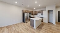Located at 1220 W Highland Blvd in Lincoln, Nebraska, this two-story home offers a thoughtfully designed layout spread across two levels. The main living level features light-toned luxury vinyl plank flooring that flows throughout the open-concept space. The kitchen is a standout, showcasing warm medium-tone cabinetry, a subway tile backsplash, stainless steel appliances, and a central island with a light quartz countertop — ideal for both meal prep and casual dining. Recessed lighting illuminates the space, which connects seamlessly to the hallway and living area. A staircase leads to the lower level, which houses an attached single-car garage with an automatic opener, providing direct interior access. The bedroom is a comfortable retreat finished with plush carpet and a ceiling fan, featuring a window with exterior views. An adjacent walk-in closet offers generous built-in shelving and hanging storage, with direct access to the full bathroom. The bathroom is finished with wood-tone cabinetry, a quartz vanity top, and a full tub-shower combo with brushed nickel fixtures. In-unit laundry with a stacked washer and dryer is conveniently accessible from the bedroom area, adding everyday practicality to this well-appointed home.