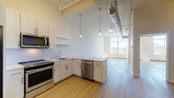 Located at 57 Cannon St in Poughkeepsie, NY, this modern unit blends industrial character with contemporary finishes throughout its single-floor layout. The open-concept living area is anchored by light wood-style flooring that flows seamlessly from room to room, while exposed spiral ductwork running along the ceiling adds a distinctive loft-inspired aesthetic.

The kitchen is well-appointed with white shaker cabinetry, a classic subway tile backsplash, light stone countertops, and a full suite of stainless steel appliances including a refrigerator, electric range, microwave, and dishwasher. Globe pendant lights hang above the peninsula, which doubles as a breakfast bar and separates the kitchen from the open living area.

Tall double-pane windows in the living space flood the interior with abundant natural light and offer views of the surrounding Poughkeepsie cityscape. Baseboard heating units run beneath the windows, ensuring year-round comfort.

The bedroom is a calm, neutral retreat featuring warm wood-tone flooring, a built-in closet with a hanging rod, and a clean panel door. The bathroom showcases a striking herringbone-patterned white tile wall surrounding a full soaking tub and shower, complemented by matte black fixtures, a white vanity, and wood-style flooring for a cohesive modern finish.