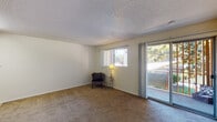 Located at 55 Newell Rd in East Palo Alto, California, this single-floor unit offers a practical and straightforward layout designed for comfortable everyday living. The open living area is generously sized, finished with wall-to-wall carpeting and neutral-toned walls that create a clean, versatile backdrop. A large sliding glass door floods the space with natural light and provides direct access to an outdoor area with views of surrounding greenery, while an additional window further enhances brightness throughout the room.

The kitchen is efficiently arranged in an L-shaped configuration, featuring warm honey-toned wood cabinetry that extends to the upper and lower walls, offering ample storage. Light speckled countertops complement the cabinetry, and the space includes a coil-burner electric range with overhead ventilation, as well as a stainless steel sink. Light wood-style flooring runs through the kitchen, adding warmth to the area.

A second carpeted room provides additional flexible living space, with a textured ceiling consistent throughout the unit and a wall vent for climate control. The bathroom is finished with light wood-style flooring, warm wood vanity cabinetry, dark countertops, and a separate water closet area, offering a functional and organized layout throughout.