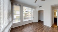 Located at 138 N Beaudry Ave in Los Angeles, this single-floor residence showcases a clean, contemporary design throughout. Rich wood-style flooring runs continuously across the entire space, anchoring the bright, neutral palette of white and warm gray walls.

The open living area is bathed in natural light through large windows and a sliding glass door fitted with horizontal blinds, offering views of the surrounding urban landscape. The space flows seamlessly, creating a generous and airy feel ideal for both everyday living and entertaining.

The kitchen stands out with striking navy blue cabinetry accented by gold hardware, contrasted by crisp white quartz countertops and a classic subway tile backsplash. Stainless steel appliances, including a gas range, refrigerator, and over-the-range microwave, complete this stylish culinary space. An adjacent laundry area adds everyday convenience.

The bedroom is well-proportioned, featuring multiple windows with blinds, a ceiling fan, and access to a dedicated closet. Additional storage is provided by a spacious walk-in closet with wire shelving. A built-in desk nook near the entryway offers a functional workspace.

The bathroom is finished with a full soaking tub and shower, a navy vanity with white countertop, and a backlit mirror, maintaining the home's cohesive modern aesthetic.