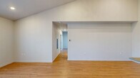 Located at 6900 NE 154th Ave in Vancouver, WA, this apartment offers a well-designed single-floor layout with three bedrooms, two bathrooms, a combined kitchen and living room, and a closet. The living area features warm light wood flooring, soaring ceilings, and access to an outdoor balcony through a glass door, allowing natural light to fill the space. A wall-mounted HVAC unit provides efficient climate control. The kitchen is a standout feature, boasting two-tone cabinetry with dark lower cabinets and white upper cabinets extending to the tall ceiling, complemented by light countertops and a full suite of stainless steel appliances including a refrigerator, range, microwave, and dishwasher. The bedrooms are carpeted for comfort, each offering sliding-door closets, with the primary bedroom featuring a dual-vanity en-suite bathroom with wood-look flooring and a tub-shower combination. The second bathroom mirrors this clean, modern aesthetic with white finishes and light flooring. Throughout, the unit maintains a bright, neutral palette with recessed lighting, creating a clean and functional living environment.