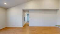 Located at 6900 NE 154th Ave in Vancouver, WA, this apartment offers a well-designed single-floor layout with three bedrooms, two bathrooms, a combined kitchen and living room, and a closet. The living area features warm light wood flooring, soaring ceilings, and access to an outdoor balcony through a glass door, allowing natural light to fill the space. A wall-mounted HVAC unit provides efficient climate control. The kitchen is a standout feature, boasting two-tone cabinetry with dark lower cabinets and white upper cabinets extending to the tall ceiling, complemented by light countertops and a full suite of stainless steel appliances including a refrigerator, range, microwave, and dishwasher. The bedrooms are carpeted for comfort, each offering sliding-door closets, with the primary bedroom featuring a dual-vanity en-suite bathroom with wood-look flooring and a tub-shower combination. The second bathroom mirrors this clean, modern aesthetic with white finishes and light flooring. Throughout, the unit maintains a bright, neutral palette with recessed lighting, creating a clean and functional living environment.