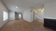 Located at 3634 Tupelo Ln in San Antonio, Texas, this two-story home offers a well-organized layout across two floors connected by a carpeted staircase with a handrail. The main living area is a standout feature, boasting dramatic vaulted ceilings with a textured finish and warm, neutral-toned carpet that extends throughout. Multiple windows fitted with horizontal blinds and vertical blind-covered sliding glass doors allow natural light to flow freely into the space, creating a bright and open atmosphere. The open floor plan creates a seamless flow between the living and dining areas, with a ceiling fan adding to the comfort of the adjoining room. The kitchen is equipped with dark espresso-toned cabinetry, stone-look countertops, wood-style flooring, and a white electric range with an overhead ventilation hood, providing a functional and classic cooking environment. Bedrooms feature plush carpeting, ceiling fans, and windows with blinds for natural light and privacy. A full bathroom includes a sliding glass shower enclosure over a tub, a toilet, and clean, simple finishes. Throughout the home, neutral wall colors, recessed lighting, and consistent flooring choices create a cohesive and comfortable living environment suited for everyday life.