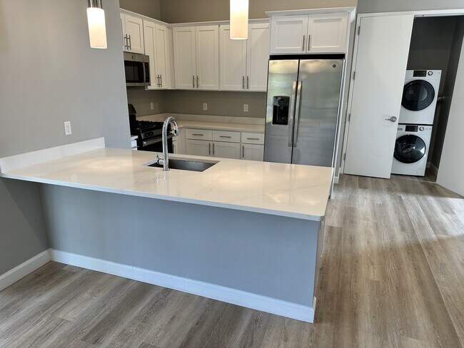 Cocina estilo galera de buen gusto con barra de desayuno de cuarzo, electrodomésticos de acero inoxidable y gabinetes de madera. - 271 Millburn Ave