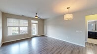 This 2-bedroom, 2-bathroom residence in Columbia, SC offers a thoughtfully designed single-floor layout that balances comfort and functionality. The open-concept living room is highlighted by rich hardwood-style flooring, a ceiling fan, a stylish pendant light fixture, and a glass door that invites natural light and provides access to an outdoor balcony area. The kitchen is a standout feature, showcasing dark espresso cabinetry, granite countertops, a mosaic tile backsplash, stainless steel appliances, and a large central island with a built-in sink — ideal for both cooking and casual dining. Both bathrooms are finished with tile flooring, dark vanity cabinetry with granite countertops, and tiled tub-shower combinations. The two bedrooms are carpeted for warmth and comfort; the primary bedroom is generously sized and features multiple windows with ample natural light, while the second bedroom is equally well-lit with a ceiling fan overhead. A dedicated in-unit laundry room houses a full-size washer and dryer with additional shelving above. Connecting hallways and a closet round out the practical layout, making this a complete and well-equipped living space.