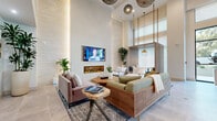 Located at 1133 Harding Place in Charlotte's vibrant 28204 corridor, this single-floor amenity space delivers a refined, resort-inspired experience through thoughtful design and high-end finishes. The main lounge commands immediate attention with its soaring double-height ceilings, textured accent walls with integrated backlighting, and a sleek linear fireplace flanked by a wall-mounted display. Curated seating arrangements — including walnut-framed sofas, live-edge coffee tables, and sculptural pendant lighting — create an inviting, layered atmosphere. Large-scale windows flood the space with natural light and offer views to the exterior, enhancing the open, airy feel. A dedicated game and entertainment zone features a shuffleboard table, ping-pong table, and a bar-height lounge nook accented with deep teal tile, open shelving, and another large display screen — ideal for social gatherings. A separate dining area with bold terracotta velvet chairs and a dark round table adds a stylish, functional node within the open-plan layout. The wide, light-filled corridor features pale hardwood flooring, recessed lighting, elevator access, and a custom mail display wall, providing a clean and welcoming transition through the space. Throughout, the design balances contemporary elegance with warm, natural materials.