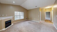 Located at 21 Stockton Ridge in Cranberry Township, PA, this single-floor residence offers three bedrooms and three full bathrooms within a thoughtfully designed layout. The galley-style kitchen is outfitted with white cabinetry featuring gold hardware, white appliances including a range, built-in microwave, dishwasher, and refrigerator, complemented by light countertops and tile flooring. A pendant light fixture illuminates the dining area at the end of the kitchen, which benefits from natural light through a window. The living room features vaulted ceilings and a large window that fills the space with natural light, creating an open and airy atmosphere. Warm tan-toned walls and neutral carpet flooring carry throughout the bedrooms and living areas, providing a cohesive aesthetic. The primary bedroom connects to a well-equipped walk-in closet with wire shelving and rack systems for ample storage. The three bathrooms include options with a soaking tub and tiled surround, as well as a standalone glass-door shower. A dedicated in-unit laundry room houses a full-size washer and dryer. Two additional closets and a hallway complete the functional floor plan of this well-appointed Cranberry Township home.