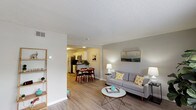 This two-floor residence features a thoughtfully designed layout with a neutral color palette and consistent wood-look flooring that flows through the main living areas. The open-concept living room provides a welcoming, airy feel, with windows along one wall allowing natural light to filter in. The space connects seamlessly to a dedicated dining area, making the layout well-suited for both everyday living and entertaining.

The kitchen is laid out in a galley configuration, featuring white cabinetry, dark countertops, a subway tile backsplash, and stainless steel appliances including a refrigerator and range. Light wood-look flooring continues here, complementing the clean, modern aesthetic.

The bedrooms offer comfortable accommodations, with carpet underfoot and closets fitted with louvered bifold doors for storage. The neutral wall tones contribute to a calm, restful atmosphere in each room.

Two bathrooms serve the unit — one with a wide vanity featuring white cabinetry, a large mirror, and wood-look flooring, and another compact bathroom with a shower-tub combination and a window providing natural light.

A dedicated in-unit laundry closet houses a full-sized side-by-side washer and dryer with wire shelving above for added storage. Throughout the space, textured ceilings and clean white trim provide a cohesive, well-maintained finish.