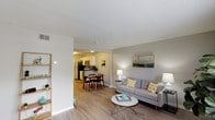 This two-floor residence features a thoughtfully designed layout with a neutral color palette and consistent wood-look flooring that flows through the main living areas. The open-concept living room provides a welcoming, airy feel, with windows along one wall allowing natural light to filter in. The space connects seamlessly to a dedicated dining area, making the layout well-suited for both everyday living and entertaining.

The kitchen is laid out in a galley configuration, featuring white cabinetry, dark countertops, a subway tile backsplash, and stainless steel appliances including a refrigerator and range. Light wood-look flooring continues here, complementing the clean, modern aesthetic.

The bedrooms offer comfortable accommodations, with carpet underfoot and closets fitted with louvered bifold doors for storage. The neutral wall tones contribute to a calm, restful atmosphere in each room.

Two bathrooms serve the unit — one with a wide vanity featuring white cabinetry, a large mirror, and wood-look flooring, and another compact bathroom with a shower-tub combination and a window providing natural light.

A dedicated in-unit laundry closet houses a full-sized side-by-side washer and dryer with wire shelving above for added storage. Throughout the space, textured ceilings and clean white trim provide a cohesive, well-maintained finish.