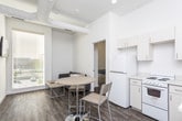 Located at 608 Main St in Clarksville, Tennessee, this single-floor unit offers a thoughtfully arranged layout designed for practical, everyday living. The kitchen is outfitted with white cabinetry, a full-size refrigerator, a range, and a microwave, and flows seamlessly into a compact dining area furnished with a round table and chairs. Recessed lighting illuminates the space, which features warm-toned hardwood-style flooring throughout the common areas. The living area provides a comfortable, open feel with neutral walls and light wood flooring, offering a relaxed setting for unwinding. The bedroom is carpeted with a patterned floor covering and includes a bed frame, a small side table, and a window fitted with blinds that allows natural light to filter in. Two bathrooms serve the unit — one features a white vanity with a sink, a framed mirror, chrome fixtures, and hardwood-style flooring, while the second includes a walk-in shower with a clean white surround and matching flooring. Throughout the unit, the design maintains a clean, minimalist aesthetic with white walls, simple finishes, and functional furnishings that create a cohesive and easy-to-maintain living environment.