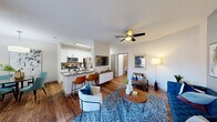 This thoughtfully designed 2-bedroom, 2-bathroom residence in Columbia, SC offers a comfortable and functional single-level layout. The open-concept living, dining, and kitchen area serves as the heart of the home, featuring warm wood-style flooring throughout and a ceiling fan overhead. The living room is bright and inviting, with a sliding glass door that opens to the outdoors and an accent wall that adds a modern touch. The adjacent dining area benefits from a large window that fills the space with natural light, complemented by an elegant overhead light fixture. The kitchen is outfitted with stainless steel appliances, white cabinetry, a gray countertop peninsula with bar seating, and a deep sink — ideal for both everyday cooking and entertaining. The primary bedroom is a well-proportioned retreat featuring carpet flooring, a ceiling fan, a window with outdoor views, and a closet. The second bedroom offers similar comfort and natural light. Both bathrooms include tiled shower/tub combinations. A dedicated in-unit laundry room houses a full-size washer and dryer with overhead shelving for added storage. Two closets and a hallway complete the well-organized floor plan, making this residence a practical and stylish home.