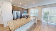 Located at 360 Village Dr in King of Prussia, PA, this well-appointed 2-bedroom, 3-bathroom residence offers a thoughtfully designed single-floor layout with contemporary finishes throughout. Light wood-tone flooring runs throughout the home, complementing the neutral, warm wall tones that lend a clean and modern aesthetic.

The open-concept kitchen and living area serves as the heart of the home. The kitchen features rich dark wood cabinetry, a granite-topped island with an undermount sink, stainless steel appliances including a French door refrigerator, microwave, and range, plus a bright window that fills the space with natural light.

The expansive living room is bathed in natural light through large floor-to-ceiling windows and sliding glass doors that offer views of lush greenery outside.

The bedrooms are comfortably sized and bright, each benefiting from windows with outdoor views. The primary bedroom includes access to a well-designed en-suite bathroom with granite countertops, dark wood vanity cabinetry, a large framed mirror, and a glass-enclosed walk-in shower. A second bathroom features elegant marble-style tile surrounding a soaking tub and shower combination. Multiple closets with wire shelving systems provide ample storage throughout.

A dedicated in-unit laundry closet houses a full-size Whirlpool front-load washer and dryer, adding everyday convenience to this polished, move-in-ready home.