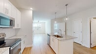 Located at 7045 Pine Forest Rd in Pensacola, FL, this one-bedroom, one-bathroom unit offers a well-designed open-concept layout with modern finishes throughout. The kitchen and living area flow seamlessly together, creating an inviting, connected space ideal for everyday living. The kitchen is a standout feature, showcasing white shaker cabinetry, a subway tile backsplash, stainless steel appliances including a refrigerator, electric range, and built-in microwave, and a center island with a granite countertop and undermount sink. Globe pendant lights hang above the island, adding a contemporary touch. Light wood flooring runs throughout the main living areas, enhancing the bright and airy atmosphere. The living room benefits from natural light through windows fitted with blinds and is finished with a ceiling fan. The bedroom is a comfortable and well-lit retreat, featuring plush carpeting, a ceiling fan, and a door providing access to a private outdoor area. A dedicated closet offers convenient storage. The bathroom is clean and modern, with a white vanity topped with granite, a framed mirror with vanity lighting, and a tiled walk-in shower.