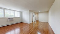 This 2-bedroom, 1-bathroom residence at 375 State St in Perth Amboy, NJ, offers a well-organized single-floor layout with a clean, functional design. Rich hardwood flooring flows throughout the living areas and bedrooms, lending warmth and continuity to the space.

The spacious living room is bright and open, featuring a large window that allows natural light to fill the room, along with a wall-mounted air conditioning unit and baseboard heating. Clean white walls provide a neutral backdrop throughout the home.

The kitchen is thoughtfully appointed with warm wood cabinetry, granite countertops, a marble-style tile backsplash, stainless steel appliances including a refrigerator and range, and a window above the sink. Light-toned tile flooring completes the space.

Both bedrooms feature the same hardwood flooring found throughout the unit. The primary bedroom is a comfortable size and includes a built-in closet with a sliding door and a rod for hanging storage. Each bedroom benefits from baseboard heating and a window-mounted air conditioning unit.

The bathroom is well-finished with a wood vanity, granite countertop, an overhead storage cabinet, light tile flooring, and a glass-enclosed tub and shower combination. A window provides natural ventilation. A hallway connects all rooms, and a dedicated closet provides additional storage.