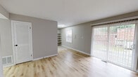 This single-story, 3-bedroom, 1-bathroom home in Indianapolis, Indiana offers a practical and comfortable layout across a compact, efficiently designed floor plan. The living room features light-toned hardwood flooring, neutral gray walls, and a sliding glass door fitted with vertical blinds that floods the space with natural light and provides access to the outdoors. Built-in open shelving adds functional storage directly off the living area. The kitchen is equipped with warm wood cabinetry, granite-style countertops, a tile backsplash, and black appliances including a refrigerator and dishwasher. Tile flooring and additional open shelving units enhance the kitchen's storage and utility. The three bedrooms are carpeted and feature neutral wall tones, with windows that bring in natural light and views of the surrounding neighborhood. The primary bedroom includes a spacious closet with built-in shelving and a sliding door. The shared bathroom is finished with tile flooring, large-format wall tiles surrounding the tub-shower combo, a wood vanity with a white countertop, and black hardware accents throughout. A hallway connects the main living spaces, completing this well-organized single-level home.