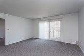 This single-floor residence offers a practical and well-organized layout across several rooms, as revealed by its 3D floor plan. The living area is generously sized, featuring neutral-toned carpet, a ceiling fan, and a large sliding glass door fitted with vertical blinds that invite natural light and provide outdoor access. The transition from the living space to the kitchen is marked by a shift to light tile flooring.

The galley-style kitchen is efficiently designed with warm oak cabinetry, dark granite countertops, and white appliances including a refrigerator and dishwasher. An electrical panel is conveniently housed within the kitchen space. Adjacent to the kitchen is an open dining or flex area that shares the same tile flooring.

The unit includes multiple bedrooms, each carpeted and finished with neutral walls. Ceiling fans are present in several rooms, and vertical blinds cover the windows throughout, providing consistent light control. The bedrooms offer comfortable proportions suitable for standard furnishings.

Two full bathrooms serve the unit, each featuring oak vanity cabinetry, dark granite countertops, undermount sinks, tub-shower combinations, and light tile flooring, presenting a cohesive and clean aesthetic throughout.