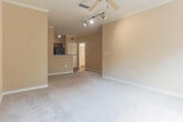 Located at 5505 Oxford Trace Way in Virginia Beach, VA, this single-floor residence offers a thoughtfully designed layout with a warm, neutral color palette throughout. The living area is generously sized, featuring plush carpeting, crown molding, a ceiling fan, and track lighting, with natural light streaming in from a large window overlooking lush greenery. Adjacent to the living space is a carpeted room with French doors that open directly onto a private balcony, offering serene outdoor views.

The kitchen is well-equipped with rich wood cabinetry, dark granite-style countertops, hardwood-style flooring, and black appliances including a refrigerator, range, and microwave. A convenient walk-in pantry or storage closet is accessible directly from the kitchen. The bathroom features hardwood-style flooring, a white vanity, and a full tub-shower combination, maintaining a clean and functional aesthetic. A spacious walk-in closet with wire shelving and carpeted flooring provides ample storage. Ceiling fans are present throughout the living and bedroom areas, enhancing comfort. The overall ambiance is bright, comfortable, and move-in ready.