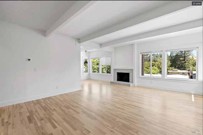 Light filled spacious beam ceiling living room with new maple wood floors and fireplace. - 300 Miller Ave