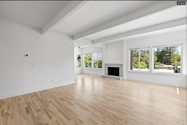 Light filled spacious beam ceiling living room with new maple wood floors and fireplace. - 300 Miller Ave